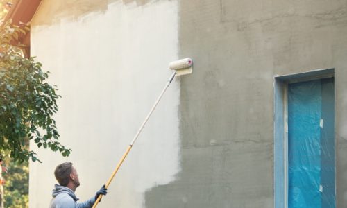 house painter painting building exterior with roller